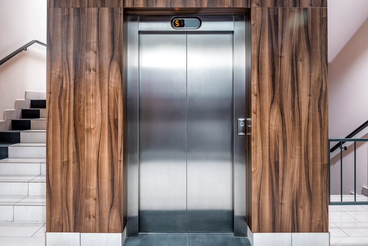 Closed elevator doors surrounded by wooden walls.